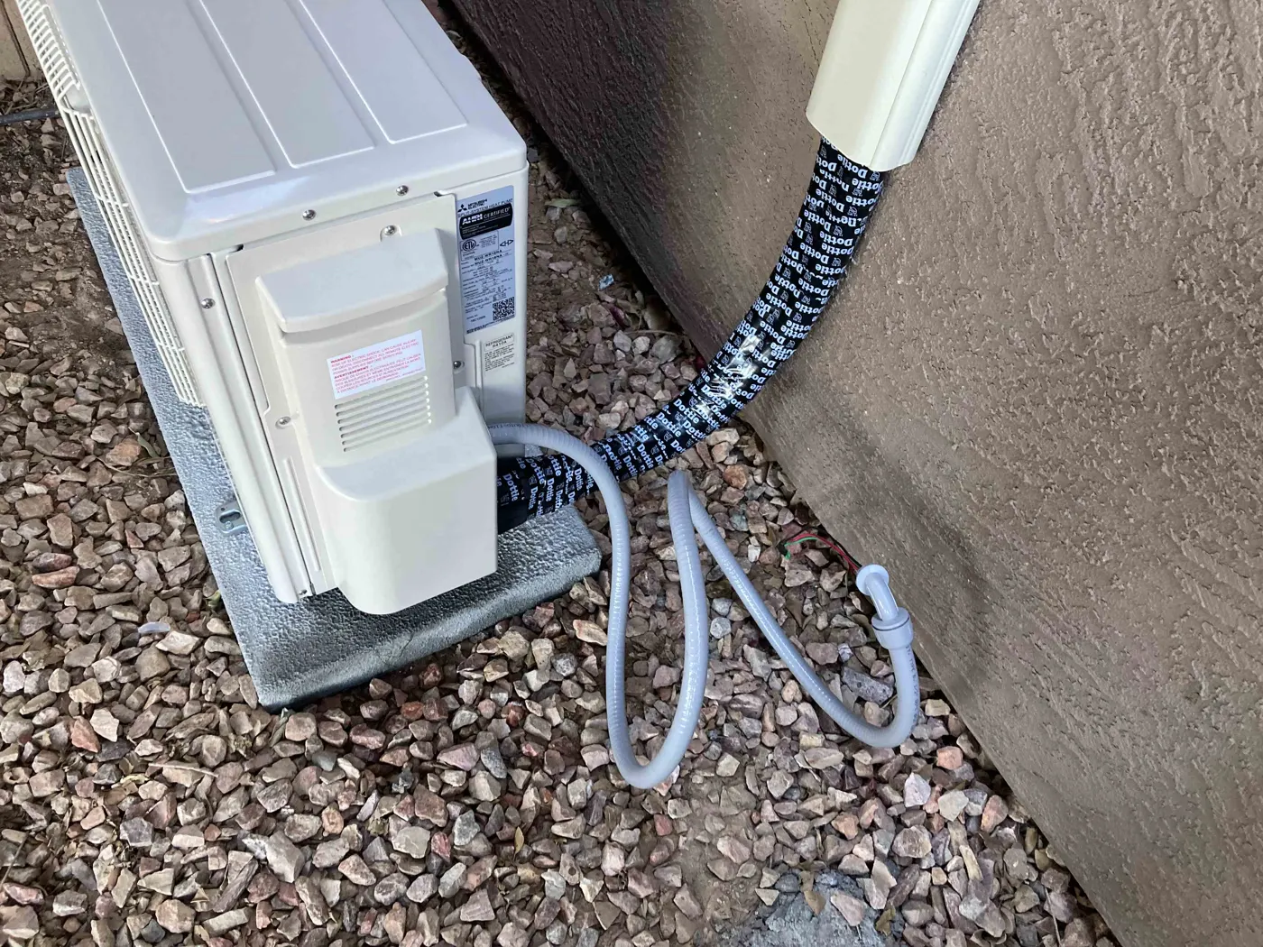 Mini split outdoor unit with line set cover along the wall